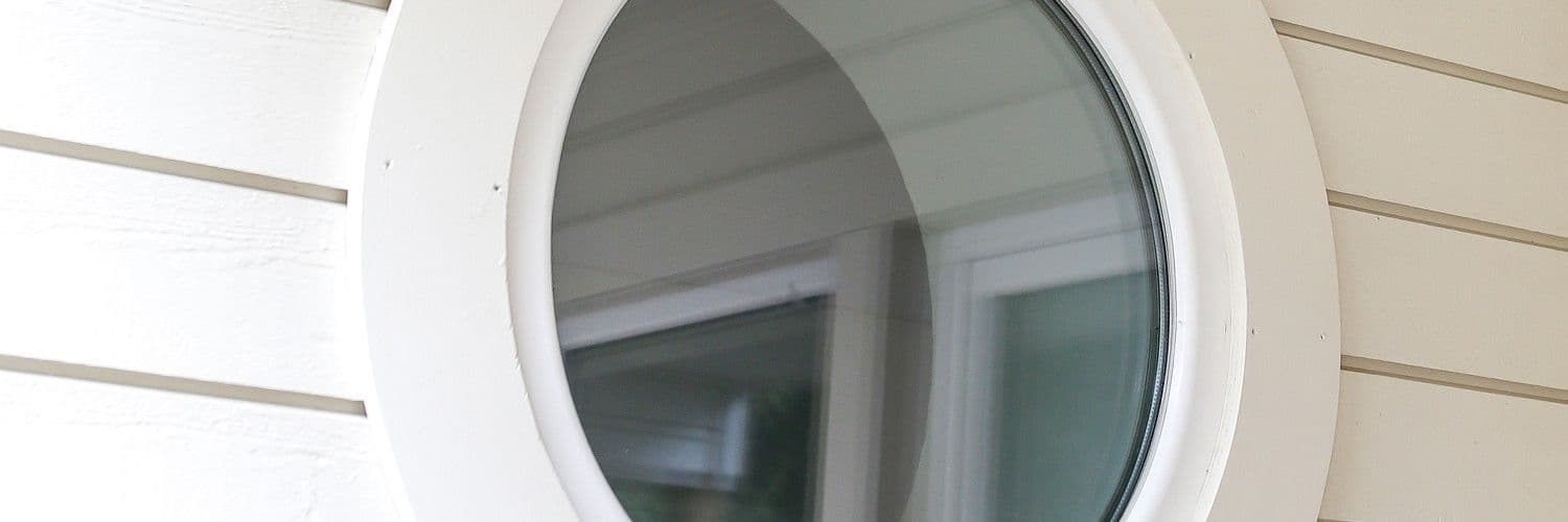 Runt fönster med vit karm på husgavel Runt fönster med vit karm på husgavel