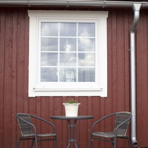 Vitt PVC fönster med spröjs på röd husfasad Vitt PVC fönster med spröjs på röd husfasad