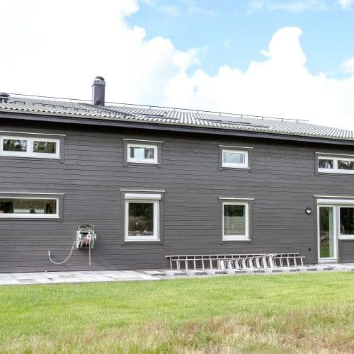 Vackra PVC-fönster mot svart fasad med liggande träpanel Vackra PVC-fönster mot svart fasad med liggande träpanel